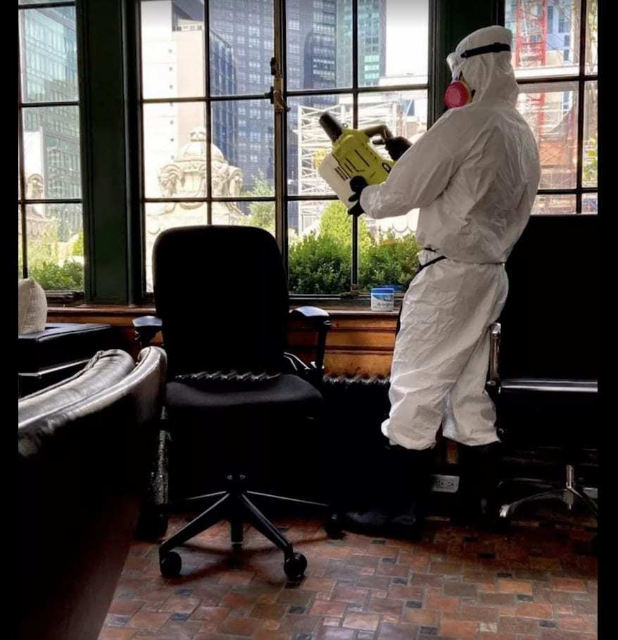 Technician in a protective suit fogging an office to treat odor